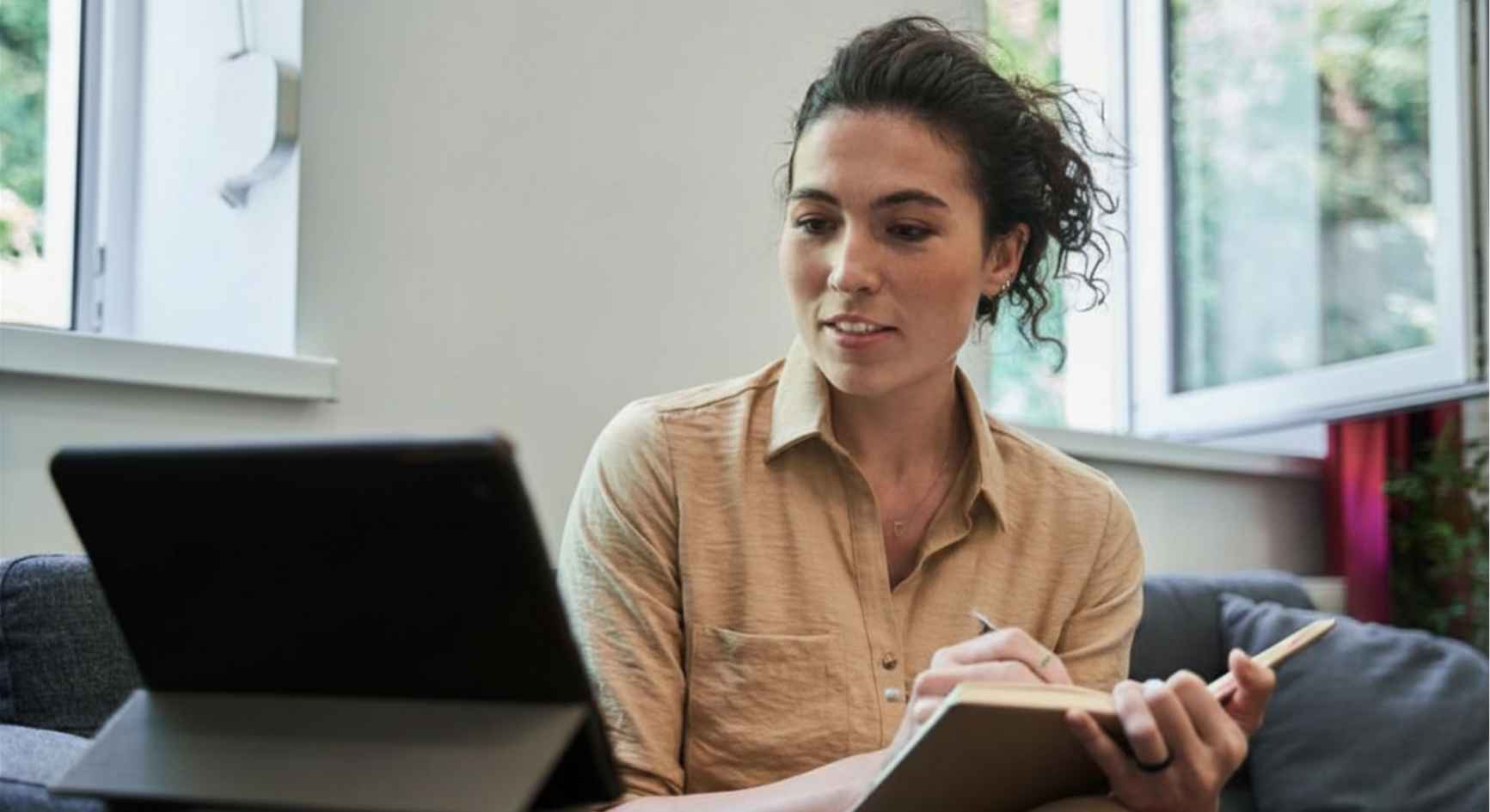 "Therapist taking notes on tablet during mental health counseling online appointment"