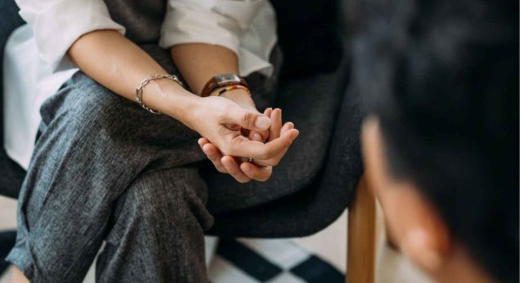Close-up of a person's folded hands during a one-on-one coaching session