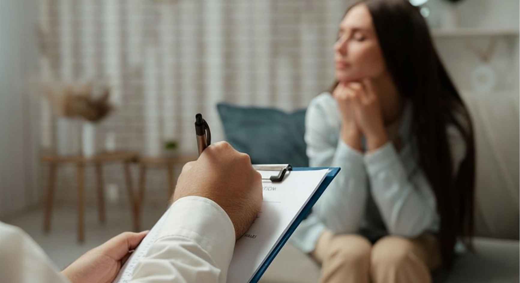 Counselor taking notes while a client reflects during a session