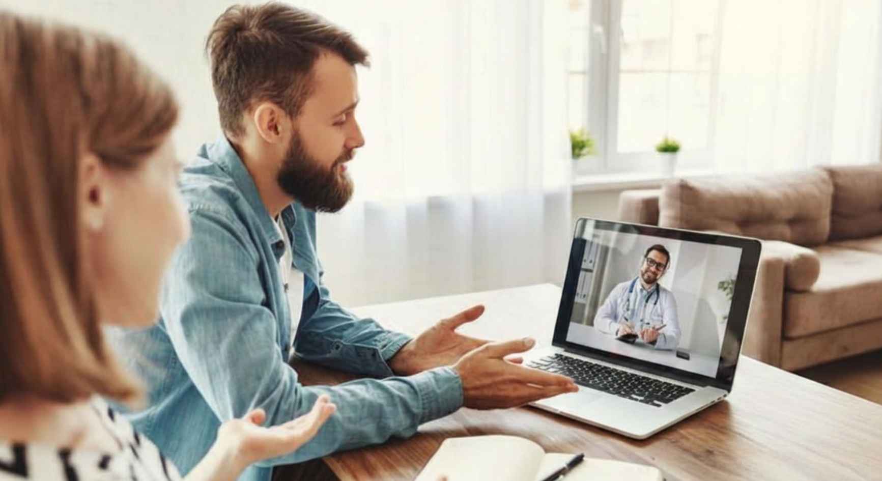 Couple on laptop video call with doctor during online counseling session at home