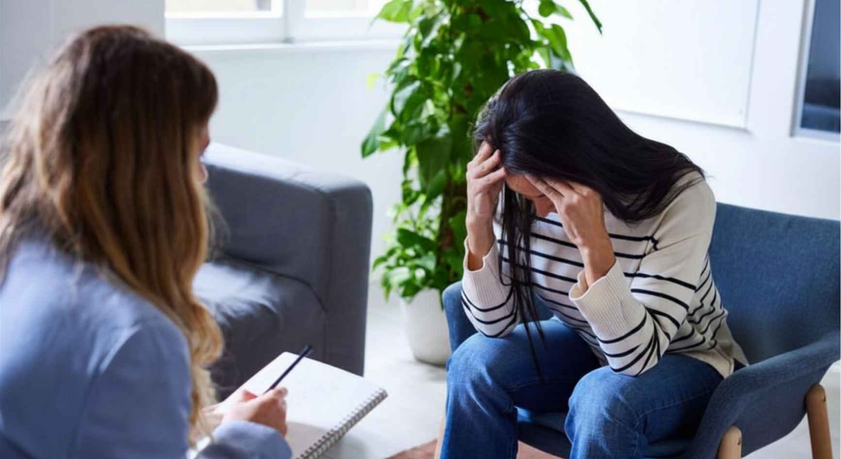 Distressed woman with her head in her hands during a therapy session with a counselor