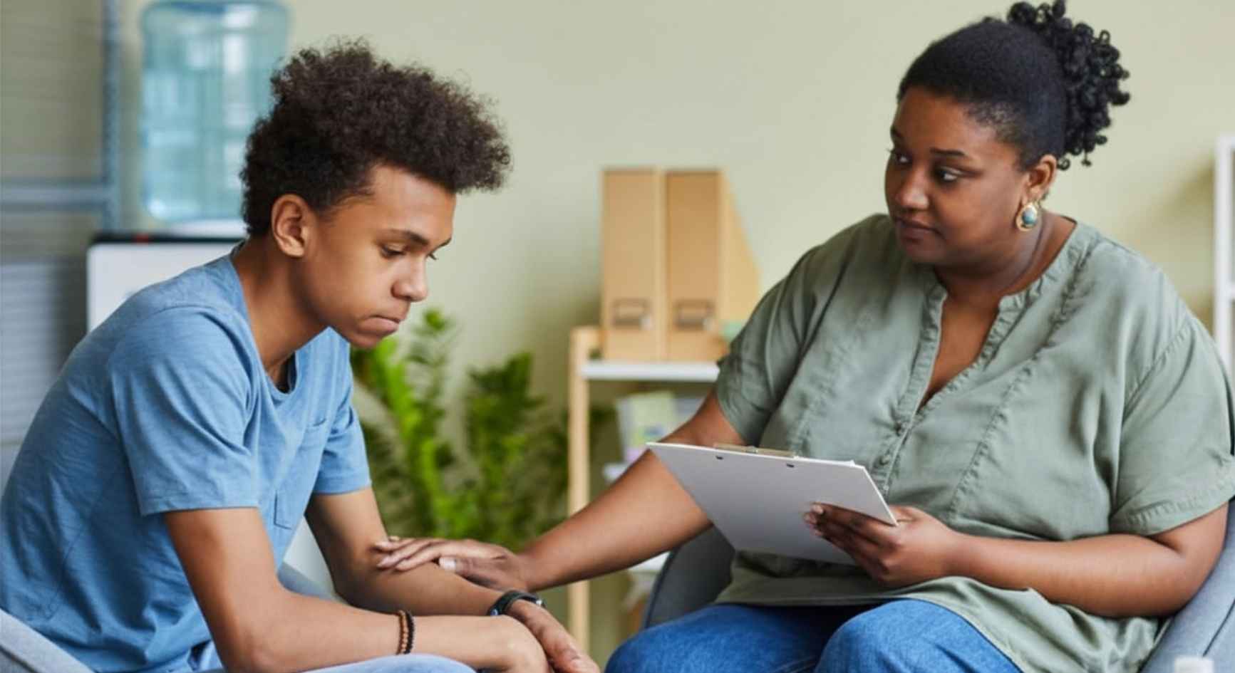 Female counselor comforting a teenage boy during a therapy session