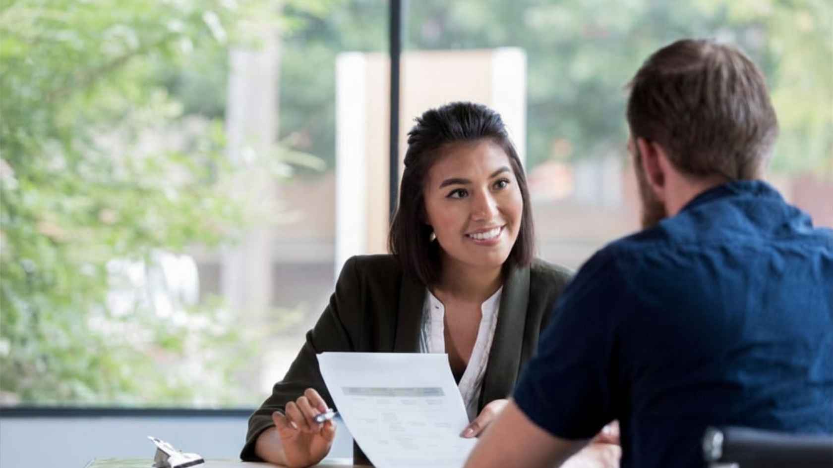 Female counselor smiling while reviewing a document with male client at desk