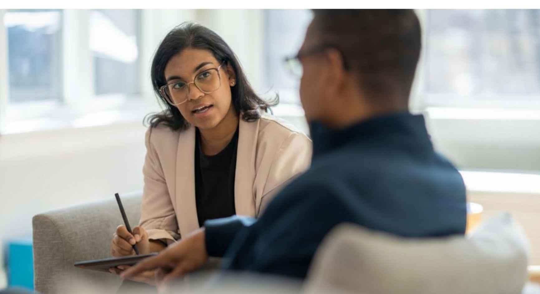 Female therapist taking notes while speaking with a client during a coaching session