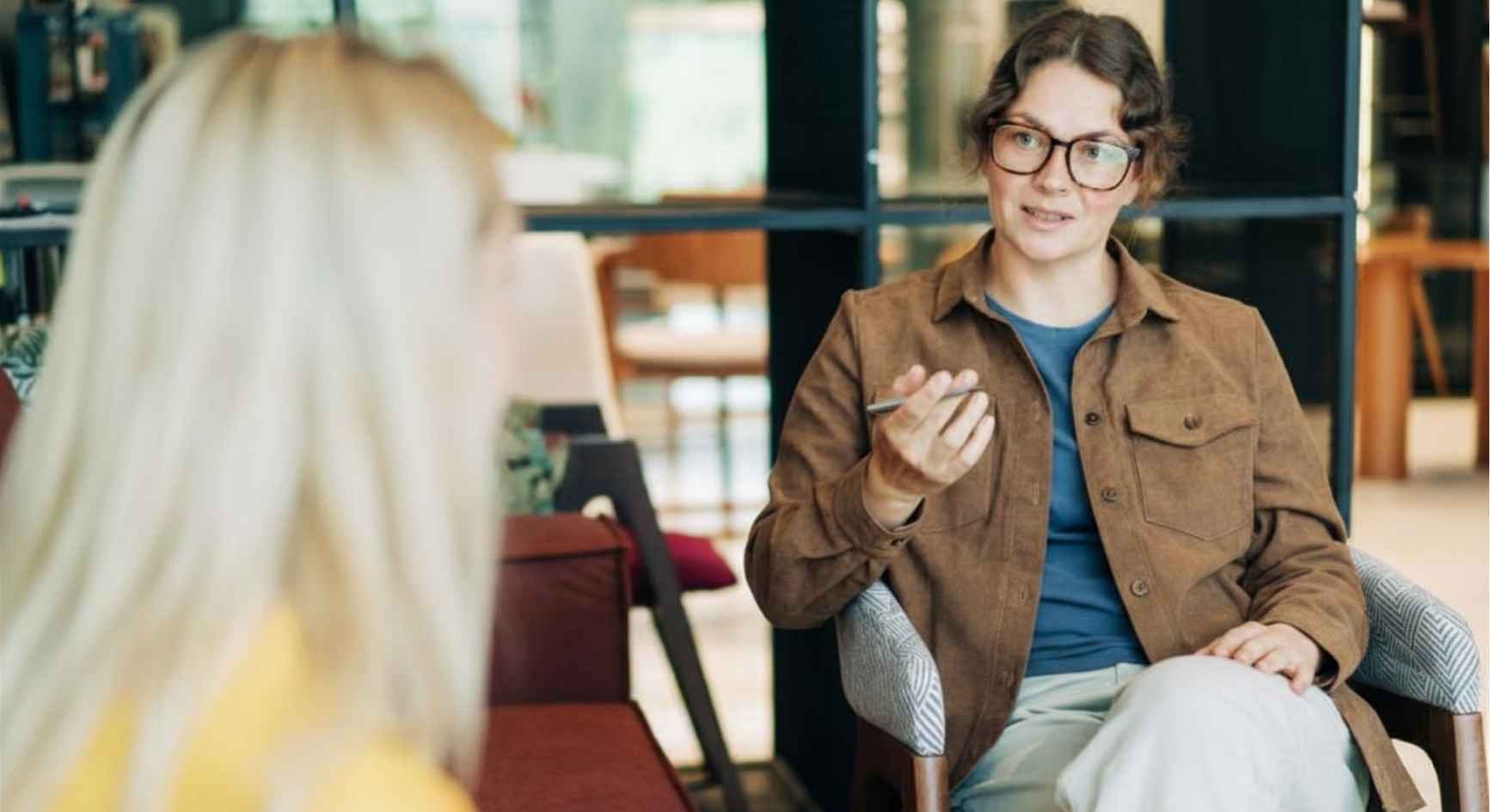 Female therapist with clipboard speaking to client during therapy session