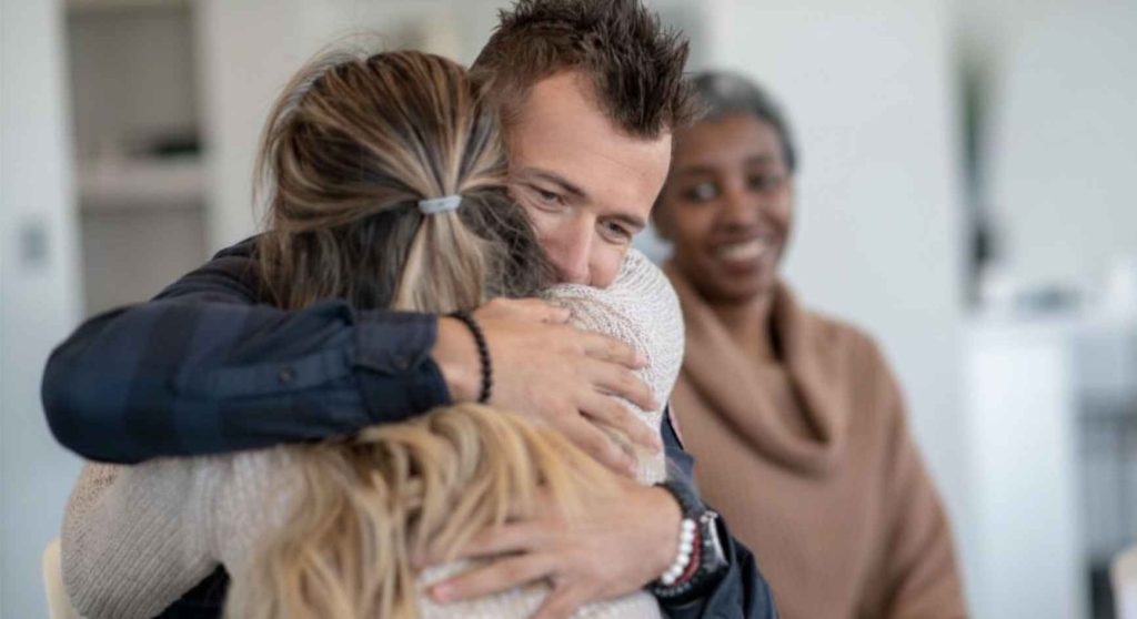 Man and woman sharing a warm hug during a support group meeting