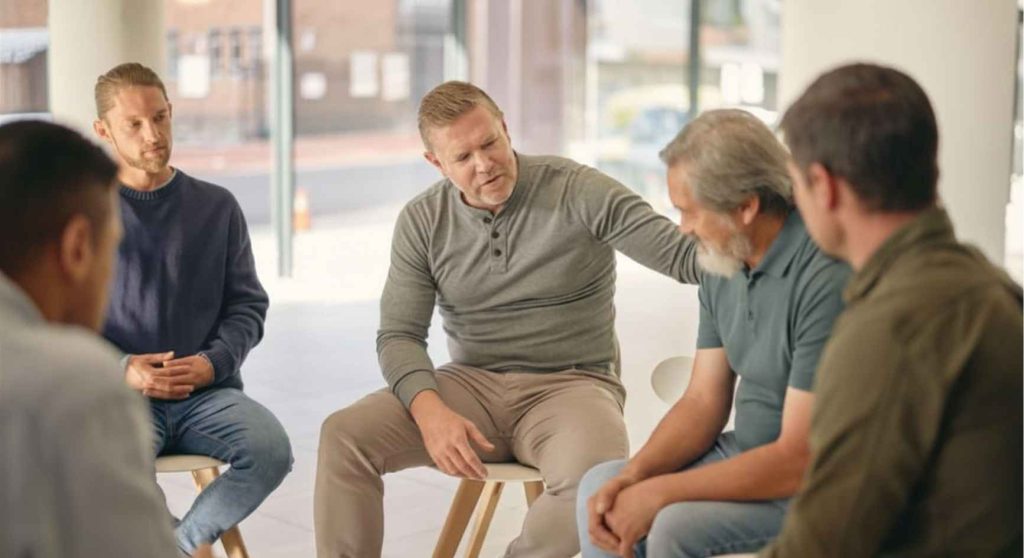 Man offering comfort to another during a men's group support meeting