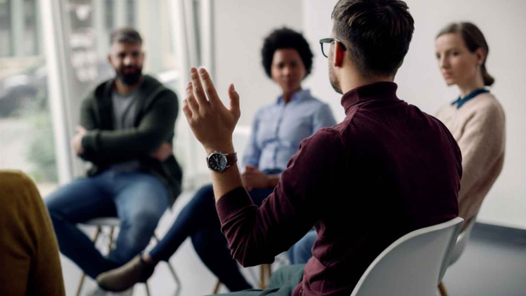 Man speaking with a raised hand during a group therapy session