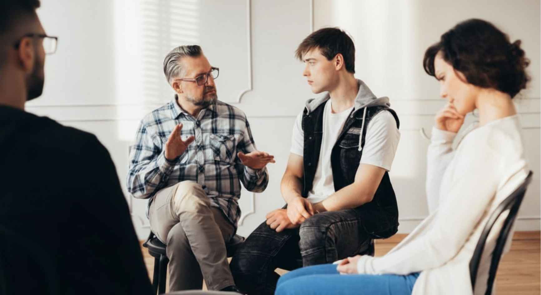 Older man talking with young man during long term recovery program support group session
