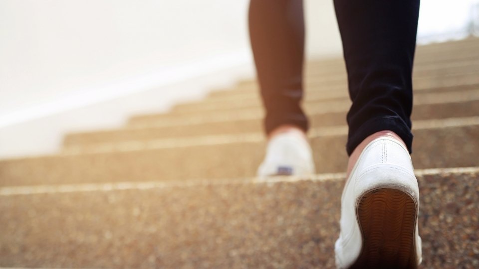 Recovery Coach vs. Sponsor is metaphorically explained by a woman walking up stairs toward recovery.
