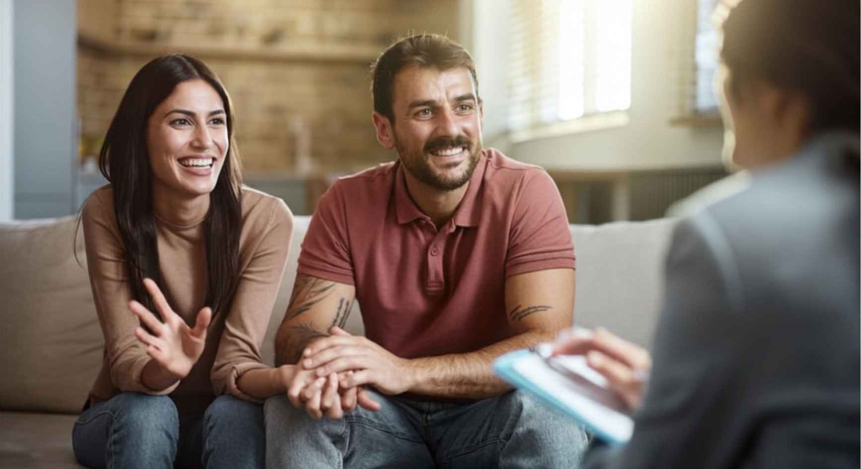 Smiling couple holding hands on couch during coaching session with therapist