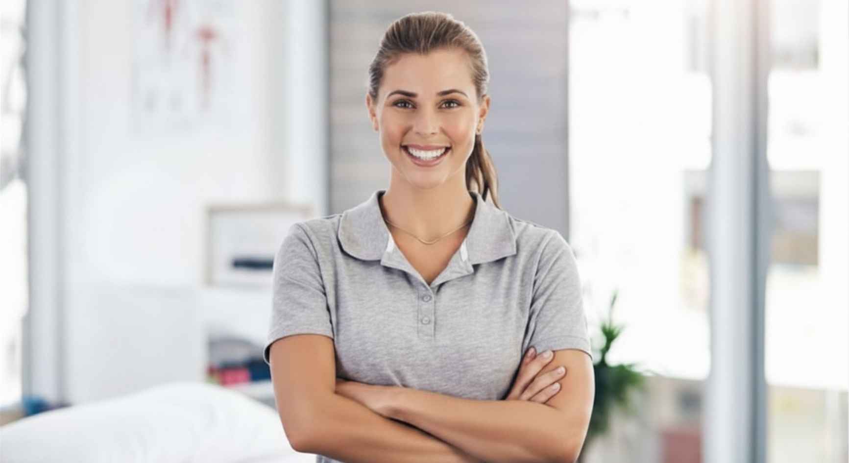 Smiling female healthcare professional with arms crossed standing in a clinic