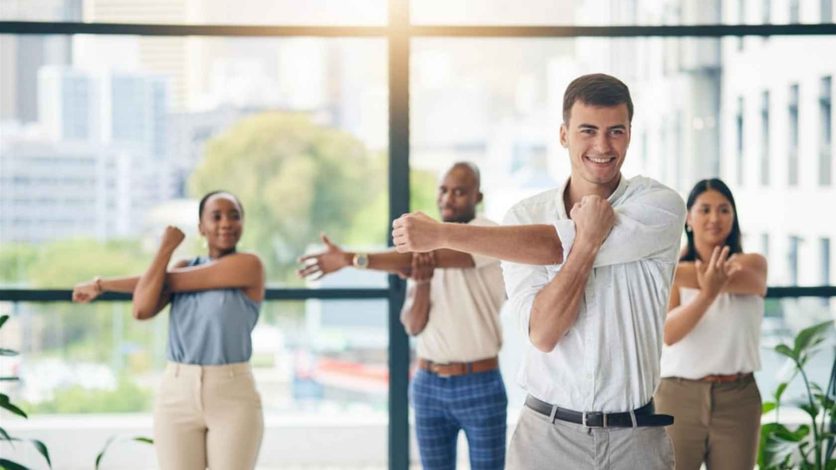 Smiling group of coworkers stretching their arms during a break in the office