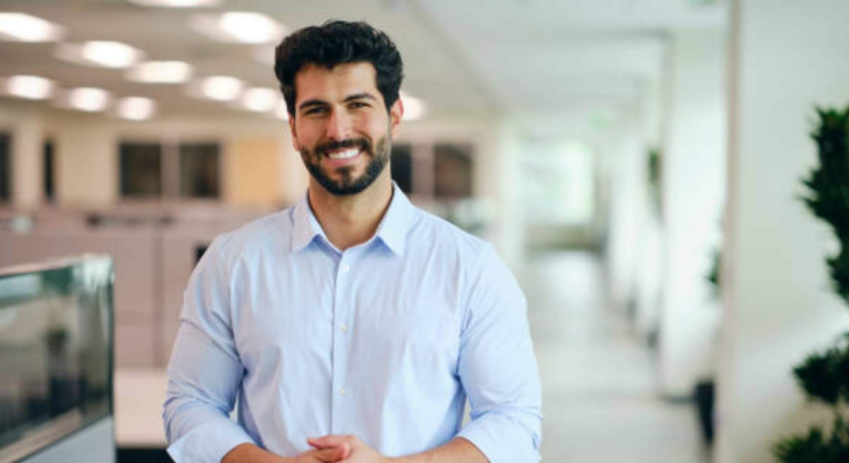 Smiling young man standing in a bright modern office
