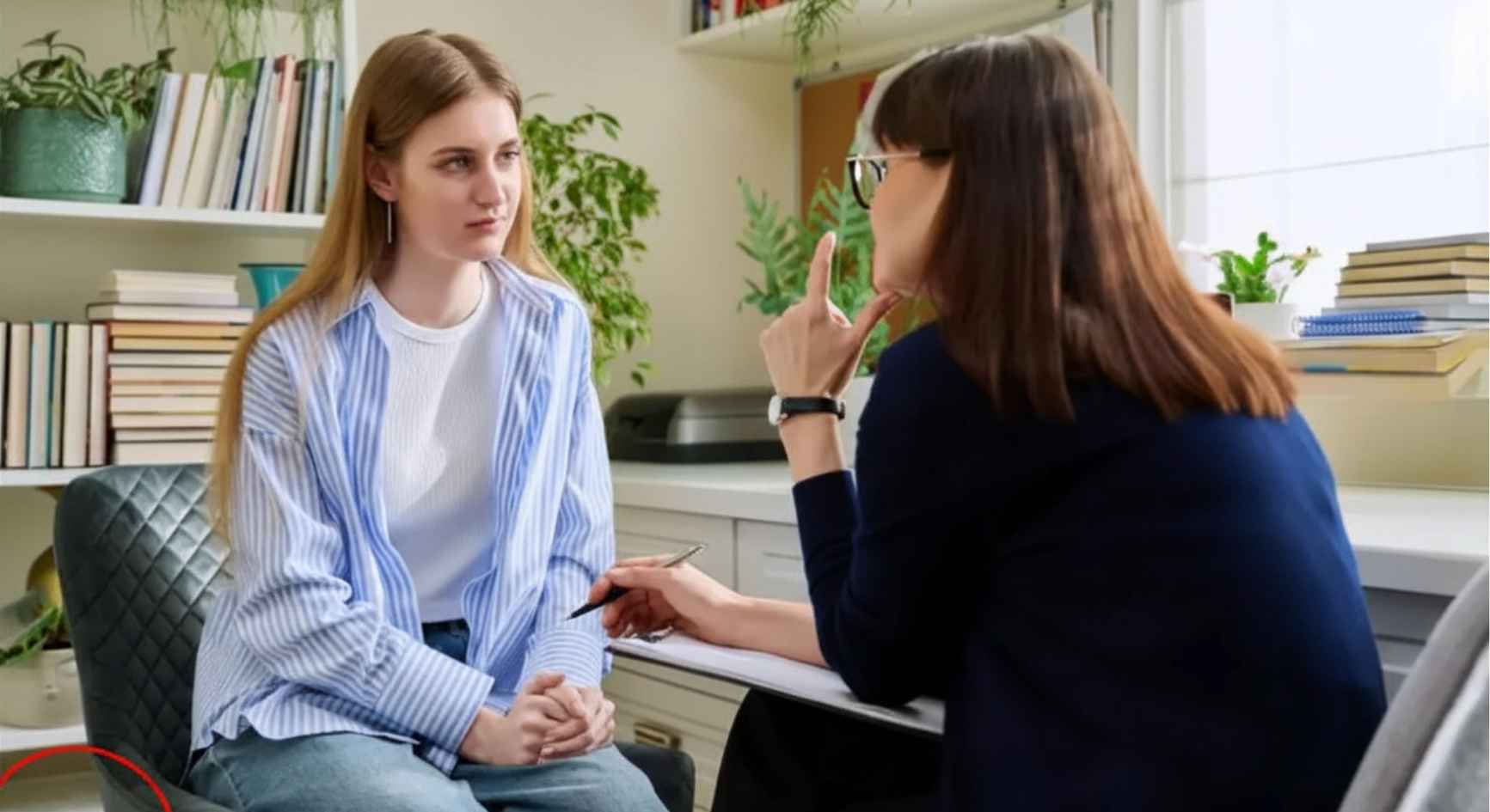 Teenage girl listening to a female counselor during a therapy session in a bright office