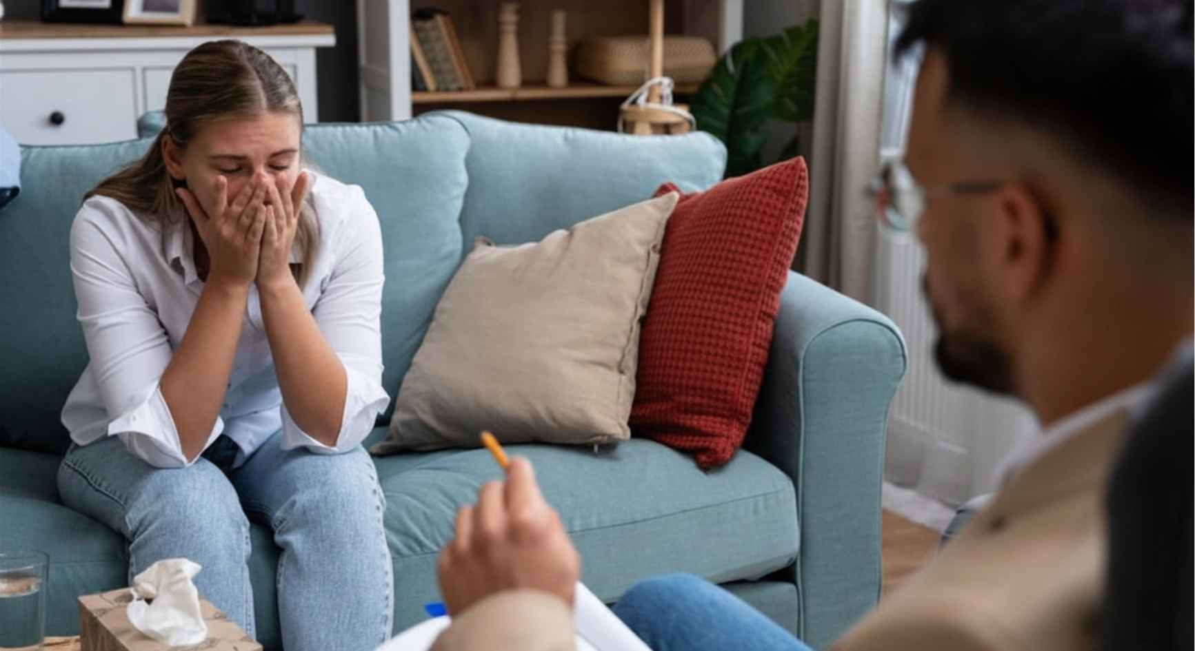 Woman crying with her hands covering her face during a therapy session with a counselor