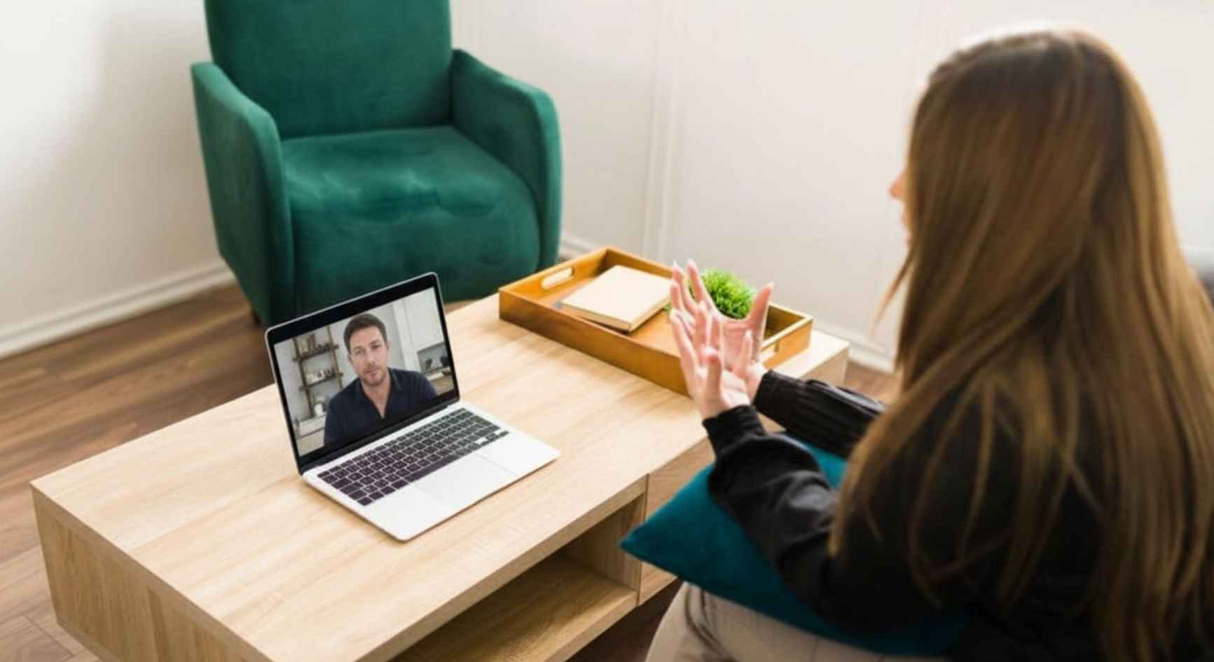 Woman on video call with male therapist during online counseling session at home