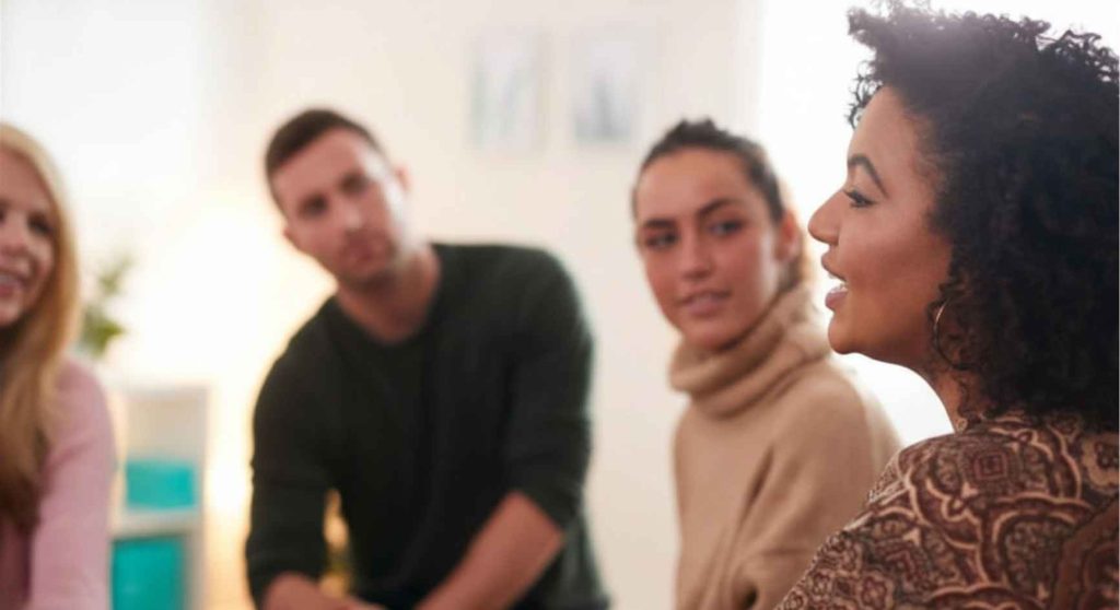 Woman speaking to attentive group members during a support group discussion