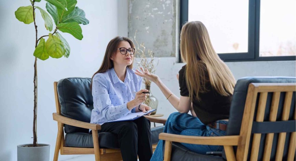 Young woman gesturing as she opens up to a psychologist in a modern office