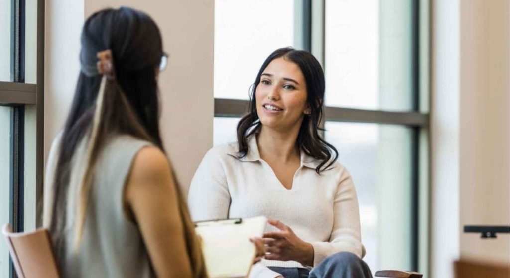 Young woman having a one-on-one conversation with a female therapist in a bright office
