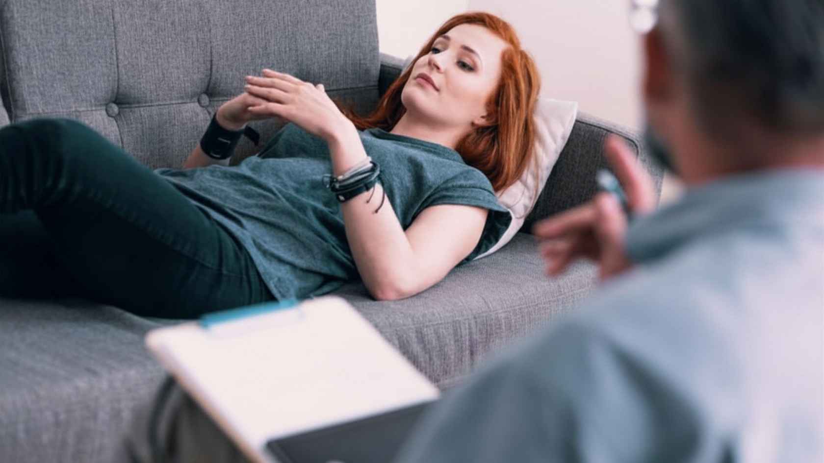 Young woman lying on a couch speaking to a male therapist during a coaching session