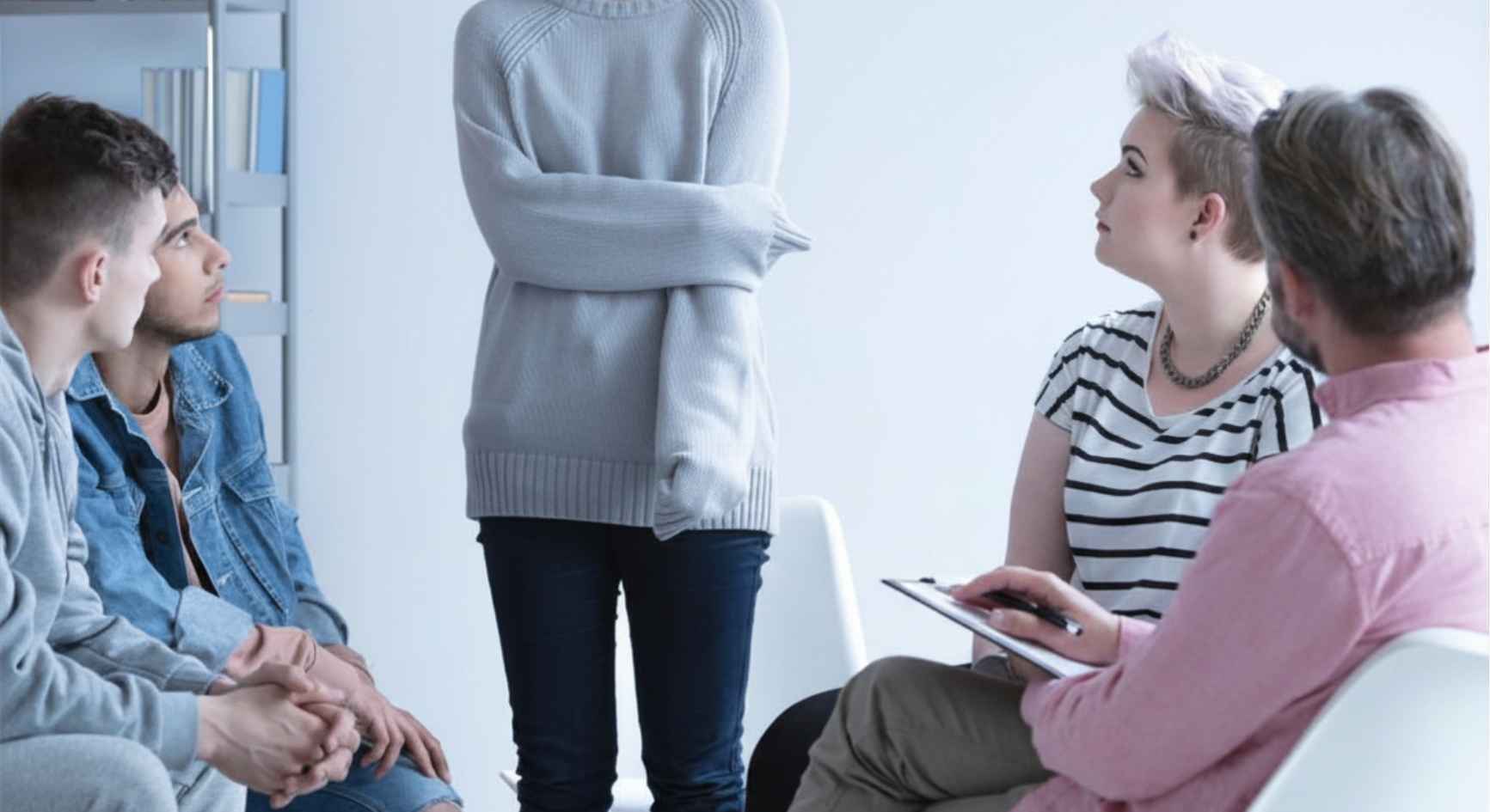 Young woman standing and sharing with a support group during a therapy session