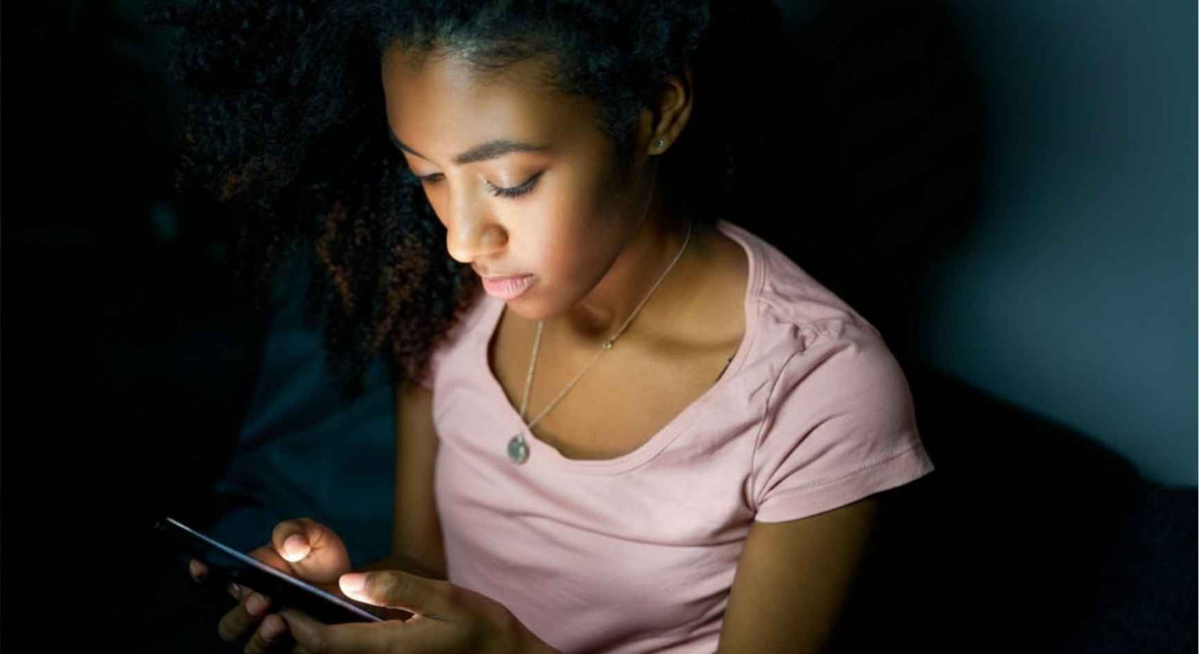 Young woman using her phone in a dark room at night